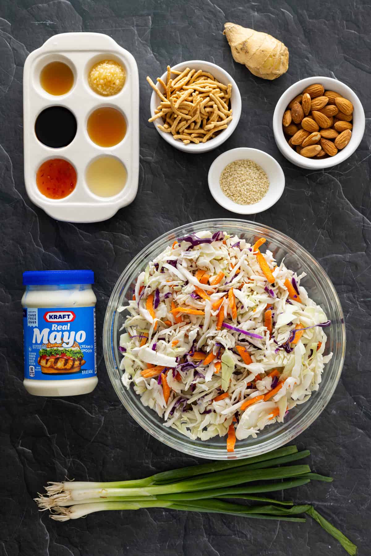 With ingredients like sweet chili sauce, ginger, and soy sauce, this Asian Coleslaw is not your basic coleslaw. Quick and easy! Overhead view of ingredients needed to make Asian coleslaw