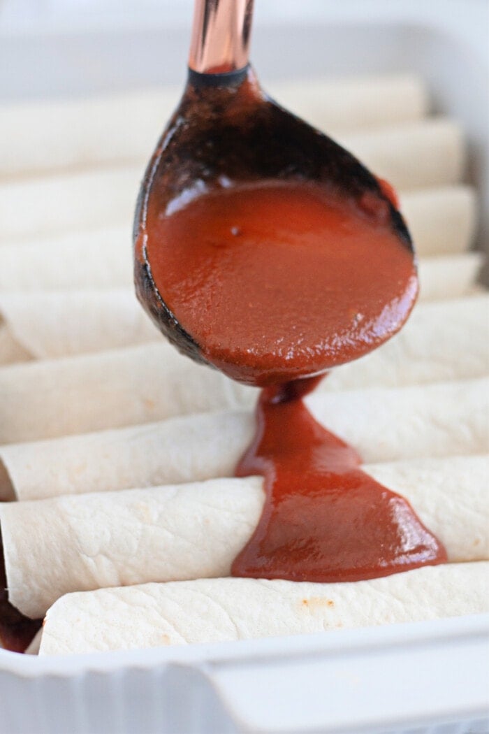 adding sauce over the prepared enchiladas