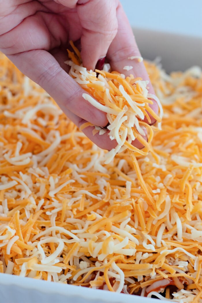 adding cheese over the prepared enchiladas