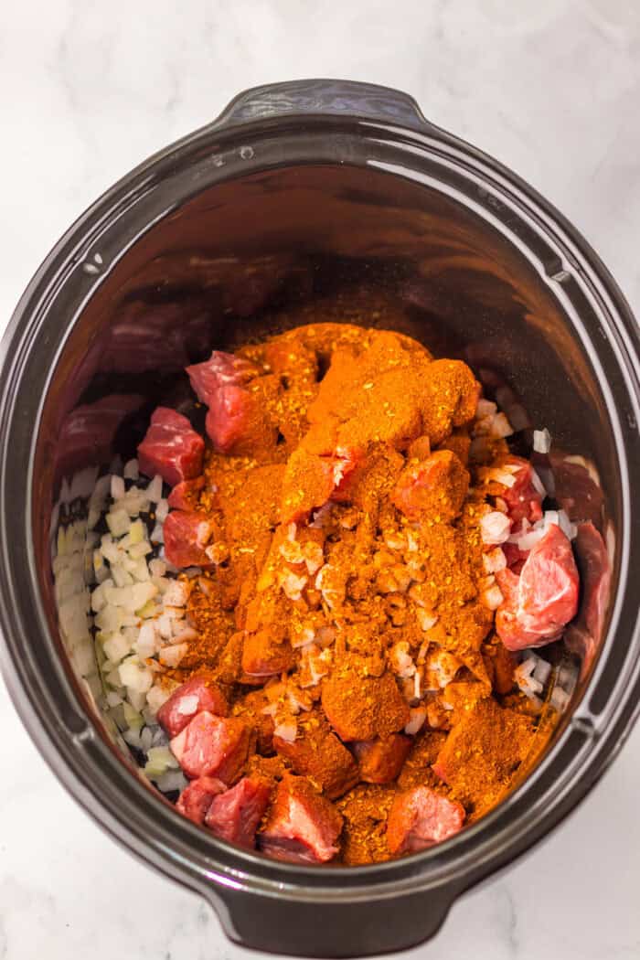 Tender birria beef slow cooks all day before getting tossed with ramen noodles and toppings in this Birria Ramen recipe. Beef stew meat. onions, garlic, and birria seasoning in a slow cooker