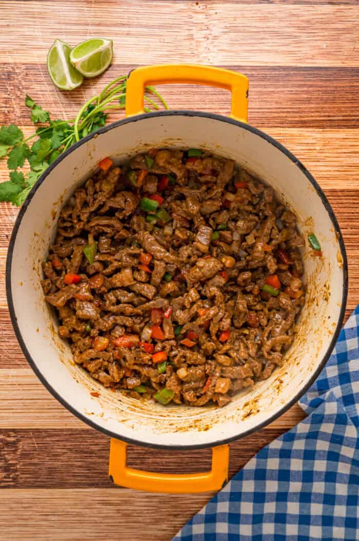 This Carne Picada recipe features braised beef and veggies in a rich, savory sauce. Serve with rice and beans or in tacos and burrito bowls. A Dutch oven of carne picada