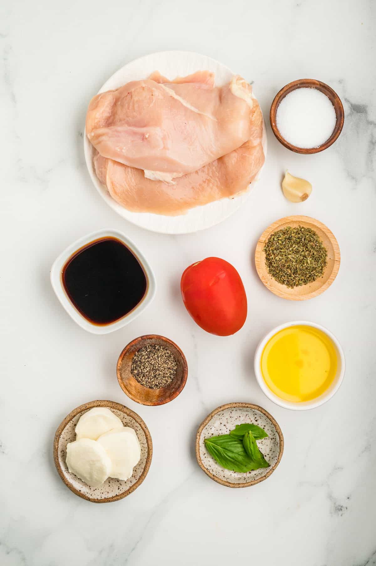 Grilled chicken breasts are topped with marinated balsamic tomatoes, fresh mozzarella, and basil in this easy Chicken Caprese recipe. Overhead view of ingredients needed to make chicken caprese