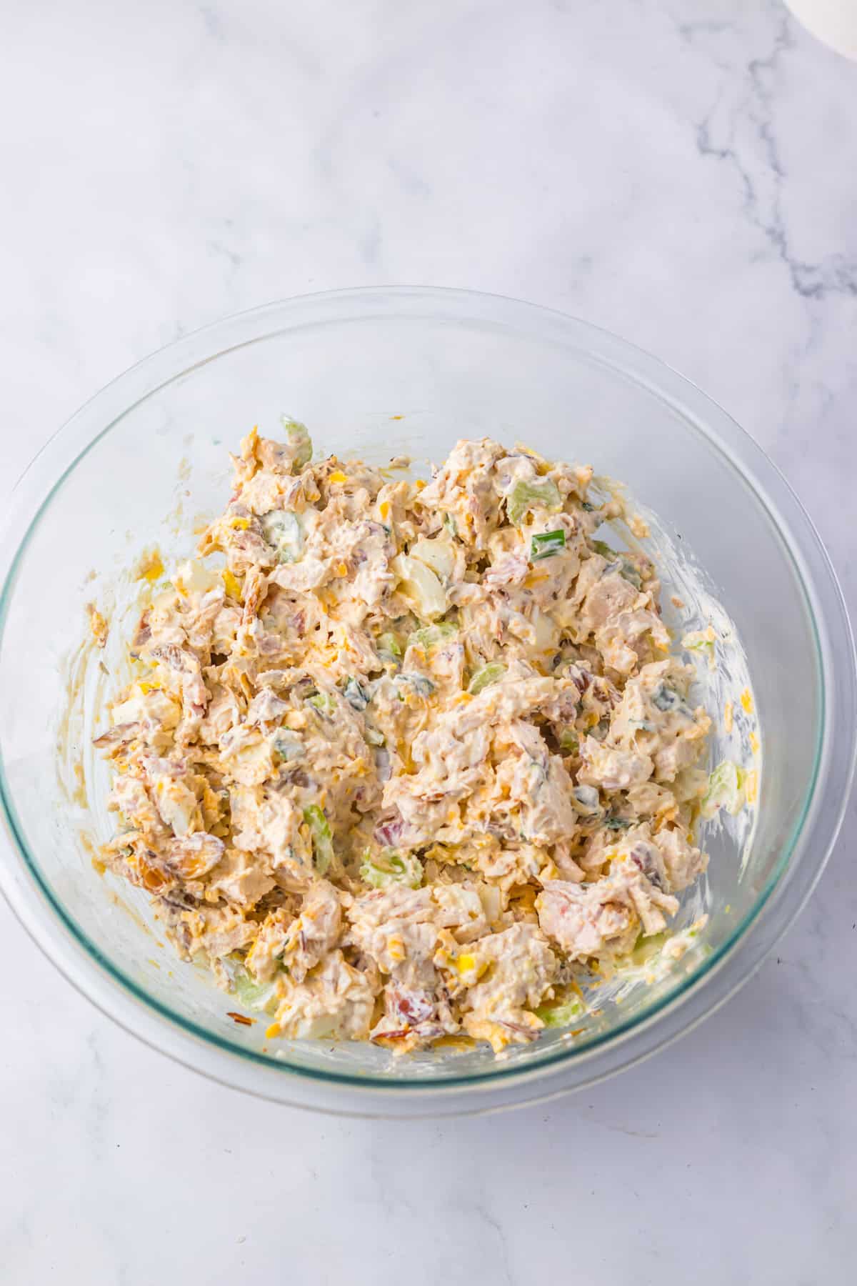 If you love chicken salad, this Million Dollar Chicken Salad with Bacon is a must-try! It’s rich, savory, and creamy with just the right amount of crunch, loaded with crispy bacon, and with balanced flavors that make it taste like a million bucks in every bite. Mixing bowl filled with creamy chicken salad made with bacon, green onions, and almonds, stirred together in a large glass bowl.