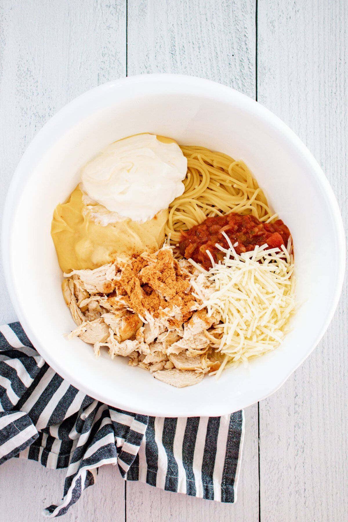 This Chicken Spaghetti Recipe is loaded with your favorite pasta flavors and uses pre-shredded or rotisserie chicken so you can have it on the table in no time. ingredients in a bowl