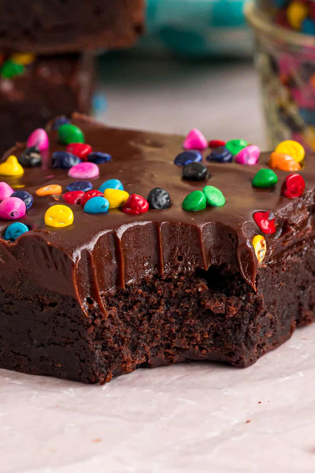 With dense, chewy brownies topped with frosting and rainbow candy-coated chocolate chips, these Cosmic Brownies are a nostalgic treat. A cosmic brownie with a bite missing