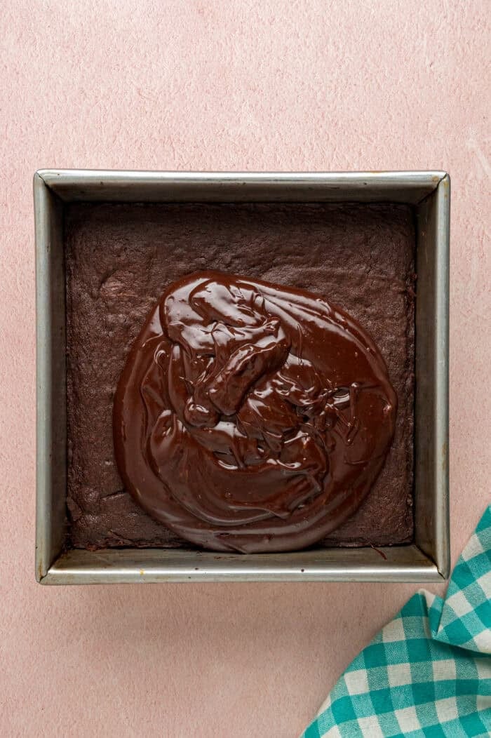 With dense, chewy brownies topped with frosting and rainbow candy-coated chocolate chips, these Cosmic Brownies are a nostalgic treat. Spreading chocolate frosting on brownies