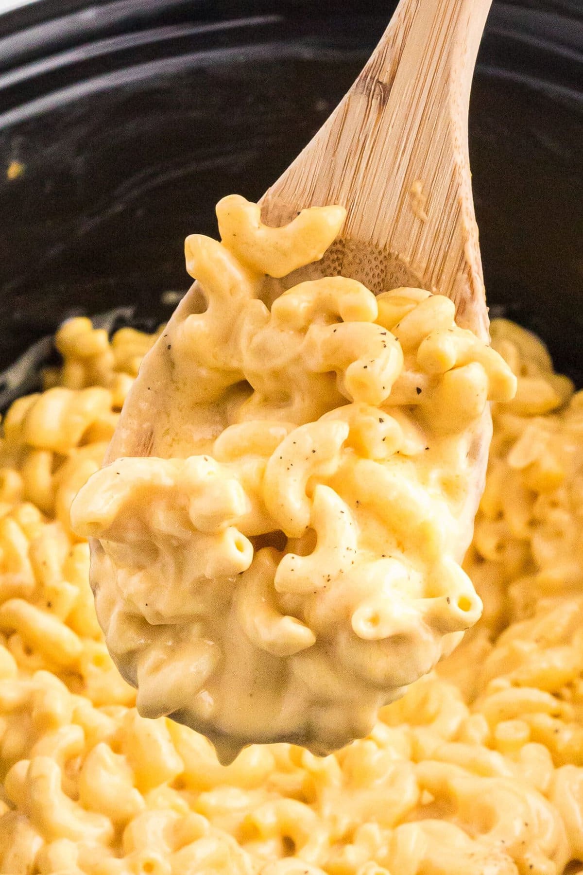 Made with a mix of cheddar and American cheeses, this Crock Pot Mac and Cheese is uber creamy and super easy to make. Mac and Cheese on a wooden spoon