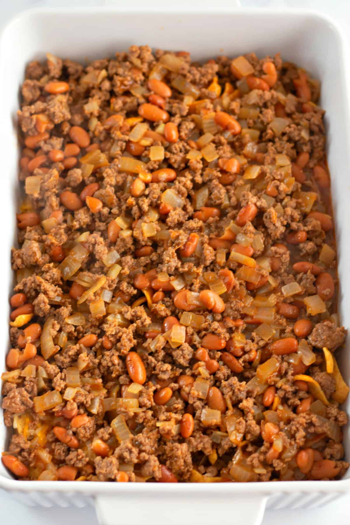 You'll love this Easy Frito Pie Recipe for a family-friendly dinner in a snap! bean and beef mixture in a baking dish