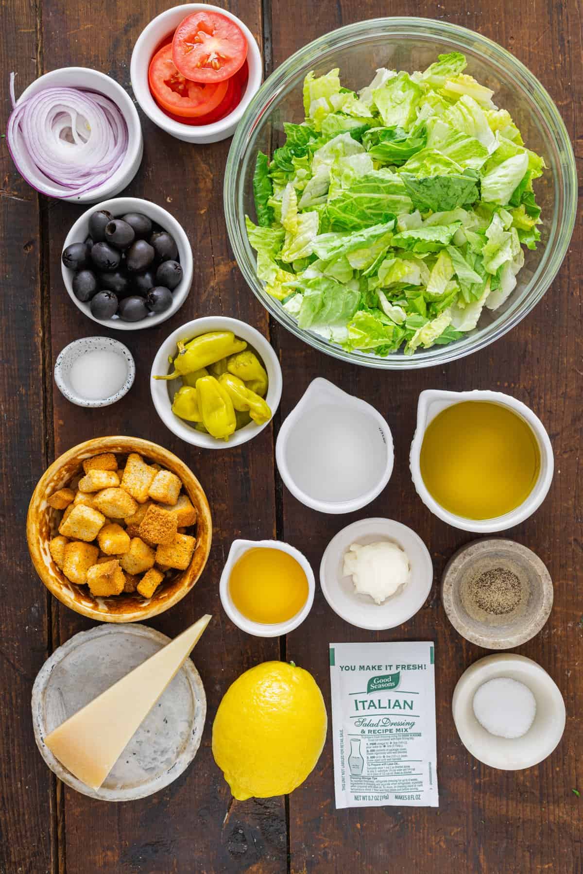 This Olive Garden Salad recipe features romaine lettuce hearts, pepperoncini, olives, and more tossed in a creamy Italian dressing. Overhead view of ingredients needed to make Olive Garden salad recipe