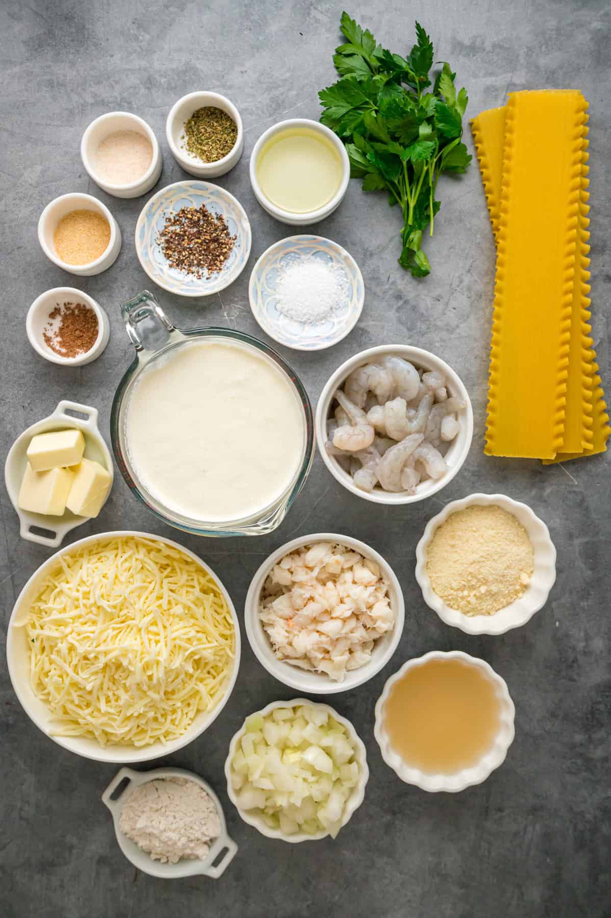 This Seafood Lasagna features layers of a creamy sauce infused with clam juice, noodles, and a shrimp and crab meat filling. Overhead view of ingredients needed to make seafood lasagna