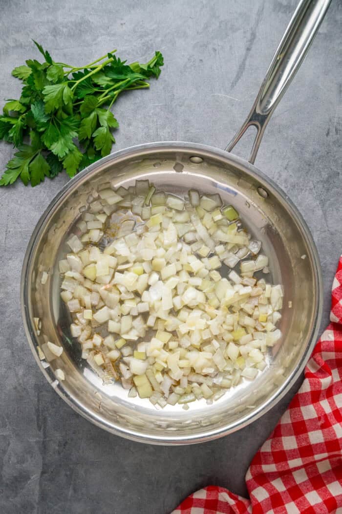 This Seafood Lasagna features layers of a creamy sauce infused with clam juice, noodles, and a shrimp and crab meat filling. Onions in a frying pan