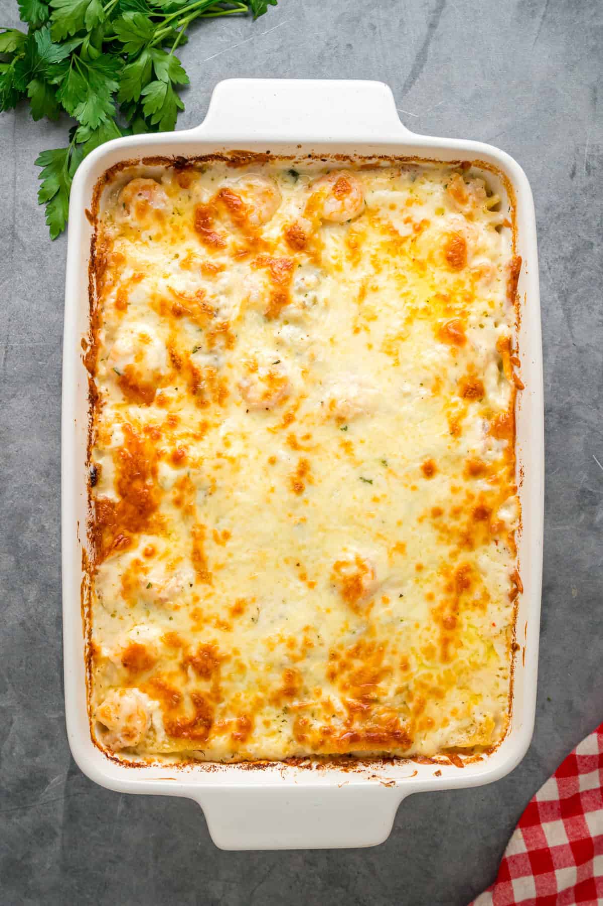 This Seafood Lasagna features layers of a creamy sauce infused with clam juice, noodles, and a shrimp and crab meat filling. Overhead view of a pan of seafood lasagna